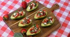 several slices of avocado with strawberries and other toppings on a cutting board