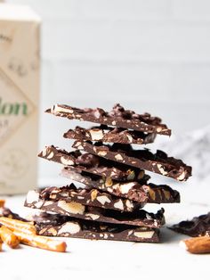 a stack of chocolate covered cookies next to a box of almonds