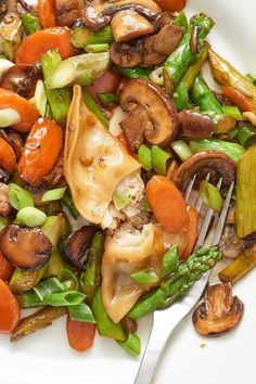 a white plate topped with mushrooms, asparagus and carrots next to a fork