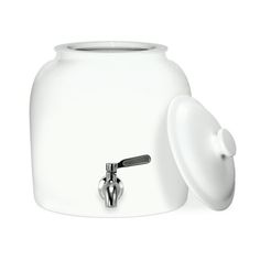 a large white jar with a lid and handle next to a small silver faucet