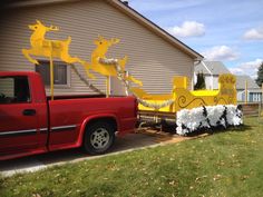 a red truck parked in front of a house with christmas decorations on the back of it