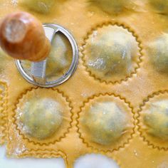 a person is making ravioli with cheese sauce and a rolling pin in the middle