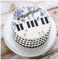 a cake decorated with blue flowers and piano keys on top of a white platter