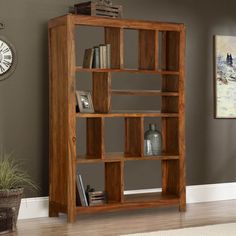 a wooden bookcase sitting on top of a hard wood floor next to a clock