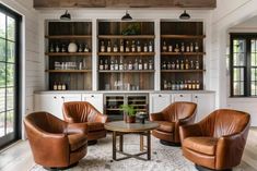 a living room filled with furniture and lots of bottles on the wall behind it's glass doors