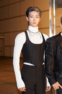 two men standing next to each other in front of a mirror wearing black and white outfits