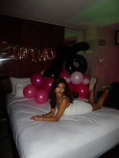 a woman laying on top of a bed next to balloons