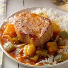 a white plate topped with meat, rice and veggies on top of a table