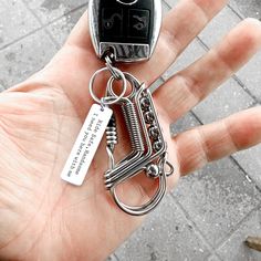 a hand holding a metal key chain with a car keychain attached to it