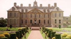 a large building with lots of hedges in front of it