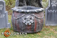 an outdoor halloween decoration with skulls and chains in a bucket on the grass next to tombstones