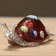 a red glass snail sitting on top of a wooden table