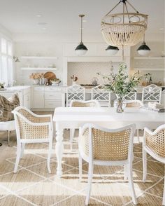 a white dining room table with chairs and a chandelier hanging from the ceiling