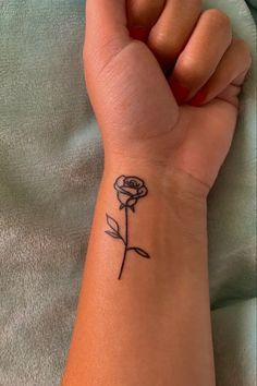 a woman's wrist with a small rose tattoo on the left side of her arm