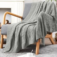 a chair with a blanket on it next to a potted plant and fire place