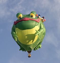 a green frog balloon flying in the sky