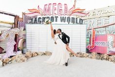 Love lights up the night! 💖 A radiant couple shares a romantic embrace amidst vintage neon signs. The bride's elegant wedding dress flows beautifully, her bouquet raised high, while the groom's classic black tux adds timeless charm. This unique backdrop featuring vibrant lights and eclectic signage makes for unforgettable wedding ideas! Explore the charm of neon museum weddings. Museum Weddings, Unique Backdrop