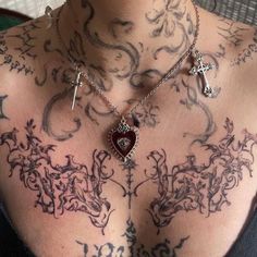 a woman with tattoos on her chest has a cross and heart pendant attached to it