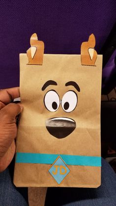 a person holding up a brown paper bag with a face drawn on it and eyes