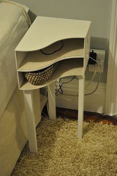 a small white table sitting on top of a carpeted floor next to a bed