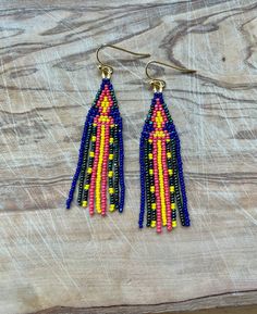 two pairs of beaded earrings on top of a wooden table