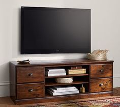 a flat screen tv sitting on top of a wooden entertainment center next to a rug