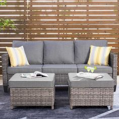 an outdoor living room with grey wicker furniture and yellow striped pillows on the floor