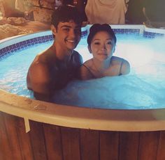 a man and woman sitting in a hot tub smiling at the camera while they pose for a photo