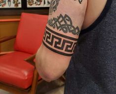 a man with a tattoo on his arm in front of a chair and red chair