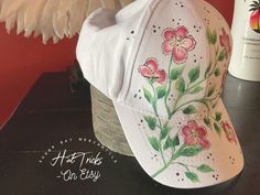 a white hat with pink flowers painted on it