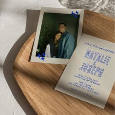 a couple is posing for a wedding photo on a wooden tray with a card in front of them