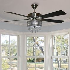 a ceiling fan in front of three windows