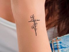 a woman's arm with a cross and flowers tattoo on the left side of her arm