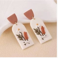 two white and pink earrings with flowers on them