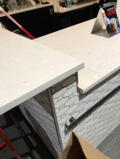 a white counter top sitting in a kitchen next to a pizza box and other items