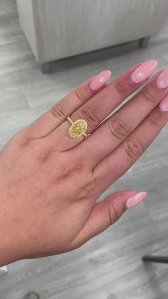 a woman's hand with pink manicures and a gold ring on it