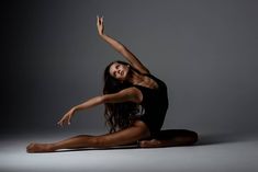 a woman is sitting on the floor with her arms in the air while she stretches