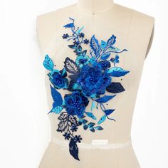 a white mannequin with blue flowers on it's back and leaves in the middle