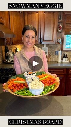 a woman holding a platter full of vegetables and dips with the words snowman veggie on it