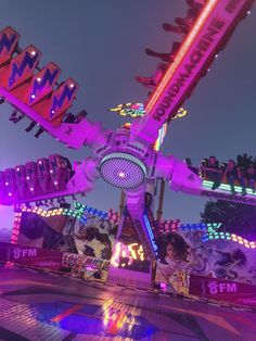 an amusement park ride at night with people on the rides and colorful lights in the background