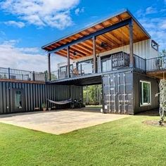 a house made out of shipping containers with a deck on the top and second story