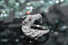 a diamond and white gold snake ring sitting on top of a black surface with lots of sparkle