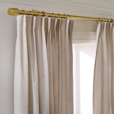 the curtains are hanging in front of a window with gold hardware on it and white walls behind them