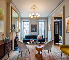 a living room filled with furniture and a fire place under a chandelier on top of a hard wood floor