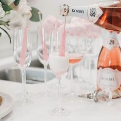 champagne being poured into wine glasses on a white table with flowers in the back ground