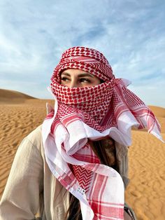 a woman wearing a red and white scarf in the desert