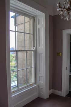 an empty room with a chandelier hanging from the ceiling next to a window