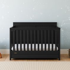 a black crib in front of a blue wall with stars and moon decals