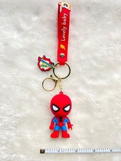 a red keychain with a spiderman figure on it and a measuring tape