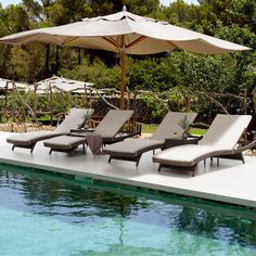 two lounge chairs and an umbrella next to a swimming pool